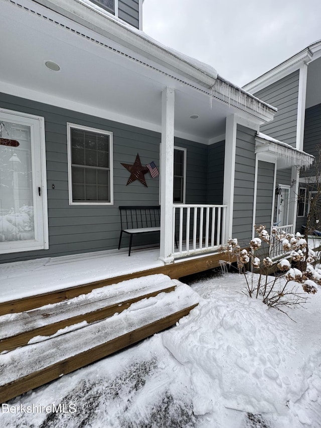 snow covered property entrance featuring covered porch