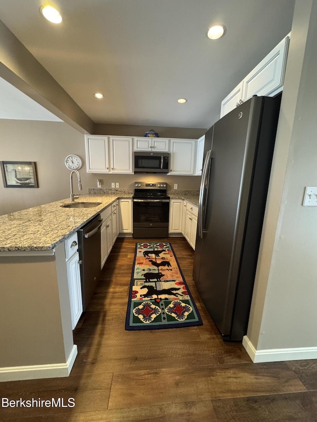 kitchen with light stone counters, stainless steel appliances, sink, dark hardwood / wood-style floors, and white cabinetry