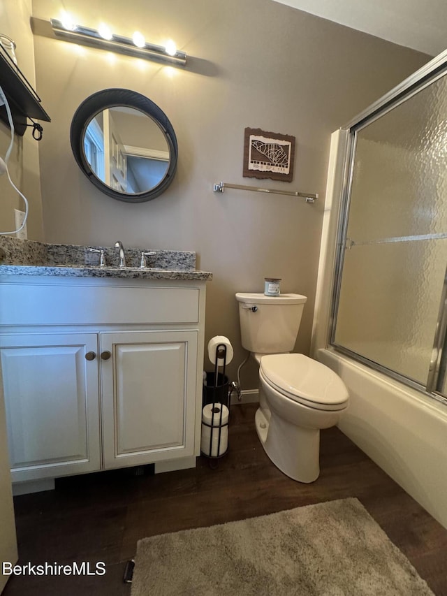 full bathroom with hardwood / wood-style floors, vanity, toilet, and shower / bath combination with glass door