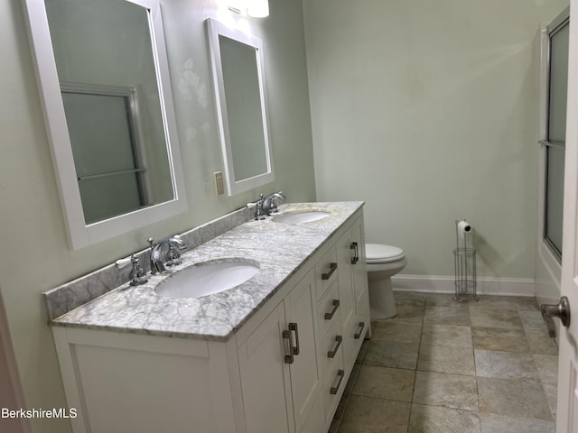 full bath featuring double vanity, toilet, baseboards, and a sink