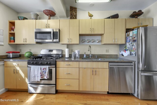 kitchen featuring light wood-type flooring, light brown cabinets, a sink, open shelves, and stainless steel appliances