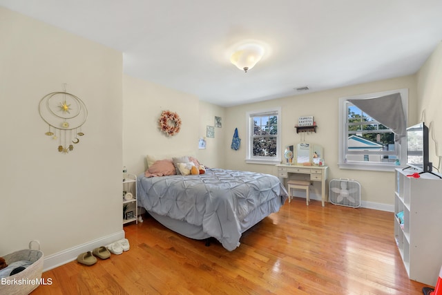 bedroom with visible vents, multiple windows, baseboards, and wood finished floors