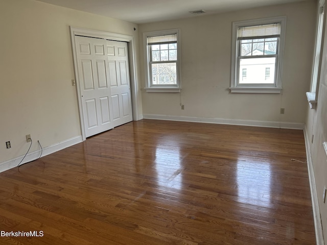 unfurnished bedroom featuring baseboards, wood finished floors, and a closet