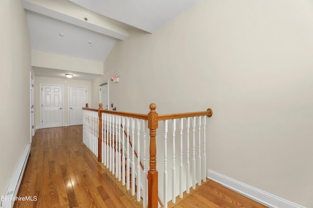 corridor with baseboard heating, lofted ceiling, baseboards, and wood finished floors