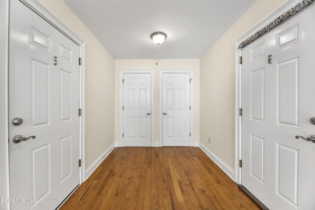 corridor featuring baseboards and wood finished floors