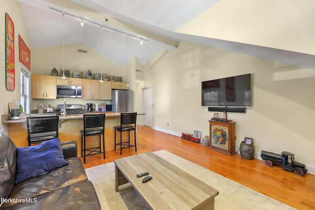 living room featuring baseboards, visible vents, light wood finished floors, high vaulted ceiling, and track lighting