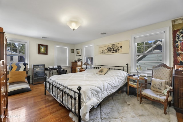 bedroom with visible vents, multiple windows, and wood finished floors