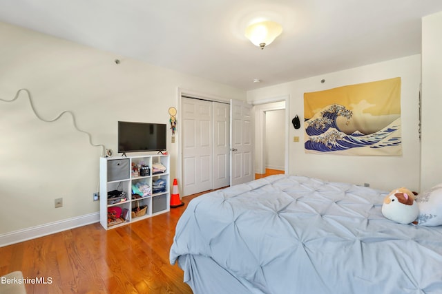 bedroom with a closet, baseboards, and wood finished floors