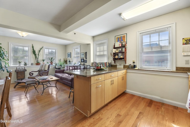 kitchen with a kitchen bar, a peninsula, light wood-style floors, and beam ceiling