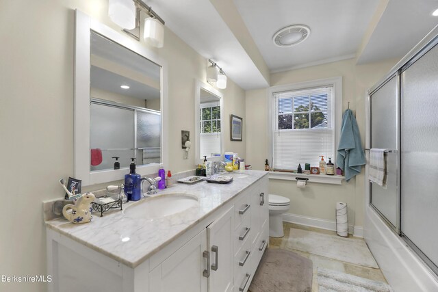 bathroom with combined bath / shower with glass door, toilet, vanity, and baseboards