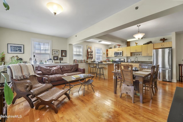 living area featuring light wood finished floors and beam ceiling