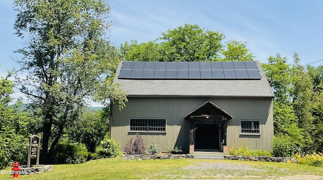 view of front facade featuring solar panels and a front lawn