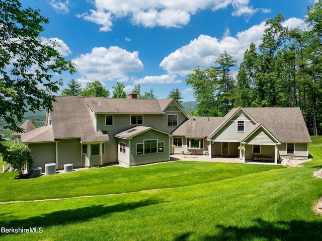 back of property featuring a lawn, central air condition unit, and a patio