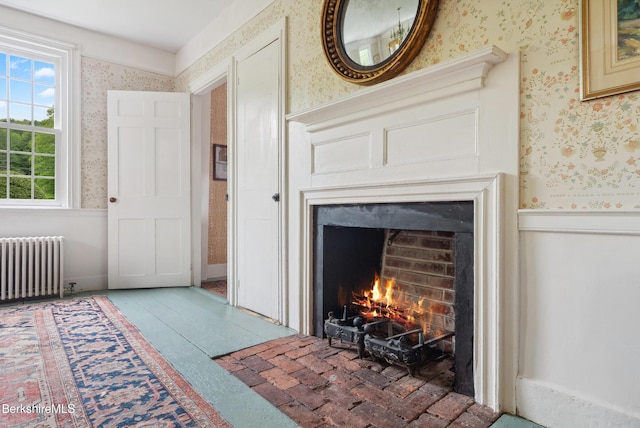 28 Main Rd, Tyringham, MA 01264 - living room featuring radiator, wallpapered walls, and a warm lit fireplace
