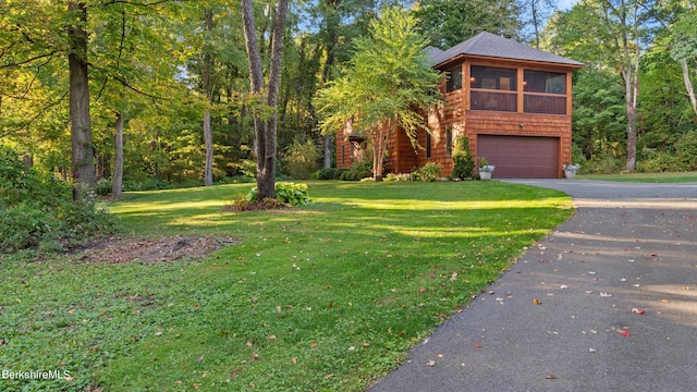 view of front of home featuring a sunroom, a front yard, and a garage