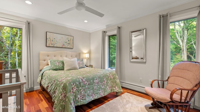 bedroom with ceiling fan, wood-type flooring, ornamental molding, and a baseboard heating unit