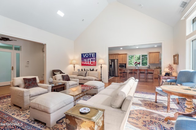 living room with ceiling fan, high vaulted ceiling, and wood-type flooring