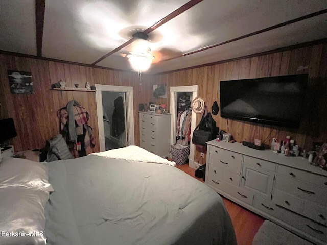 bedroom with ceiling fan, a closet, a spacious closet, and wood walls