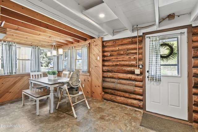 dining room with rustic walls and beam ceiling