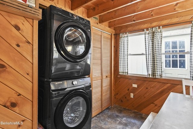 laundry area featuring stacked washer and dryer, laundry area, and wood walls