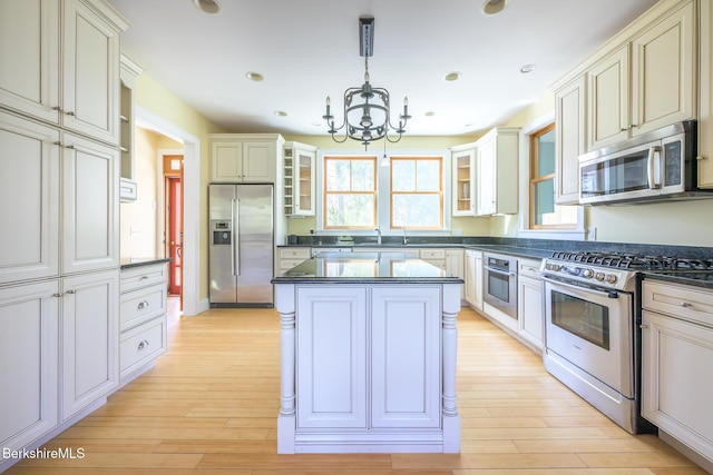 kitchen with a chandelier, dark countertops, appliances with stainless steel finishes, and glass insert cabinets