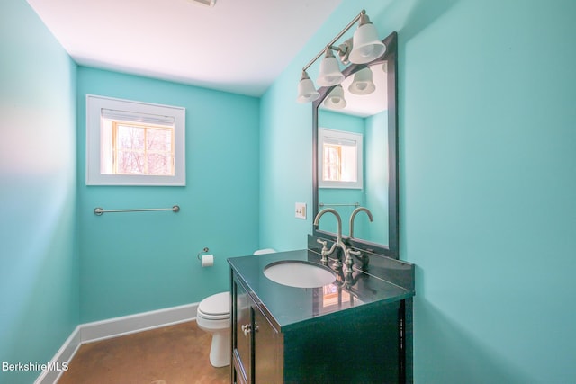 half bath with toilet, baseboards, a wealth of natural light, and vanity