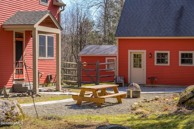 view of outdoor structure featuring an outdoor fire pit, fence, and entry steps