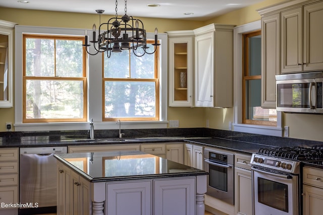 kitchen with a kitchen island, appliances with stainless steel finishes, hanging light fixtures, a sink, and a notable chandelier
