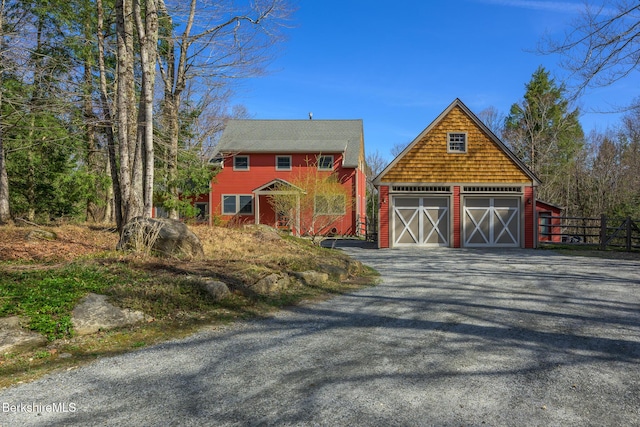 view of front of house featuring a barn, fence, an outdoor structure, and a detached garage
