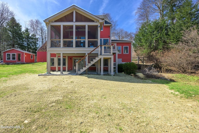back of house with a sunroom, a lawn, a wooden deck, and stairs