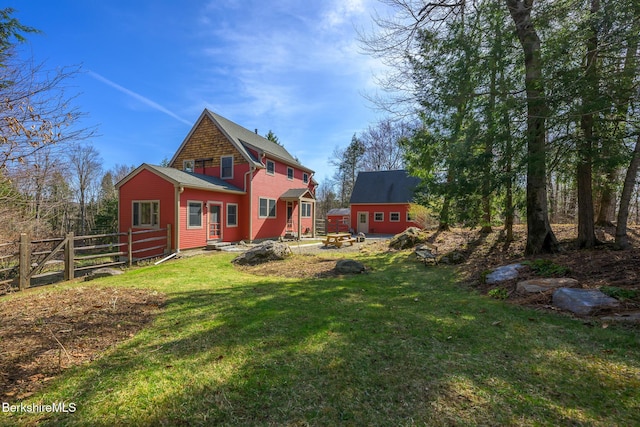 back of property with fence, entry steps, and a yard