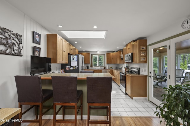 4 Birch Hill Rd, Peru, MA 01235 - kitchen featuring stainless steel appliances, a peninsula, a skylight, a breakfast bar, and light countertops