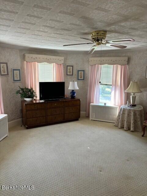 bedroom featuring radiator, ceiling fan, light carpet, and multiple windows