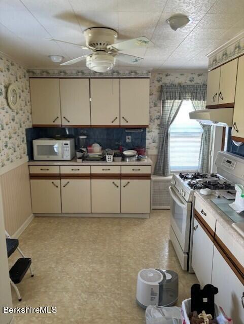 kitchen featuring cream cabinetry, white appliances, and ceiling fan