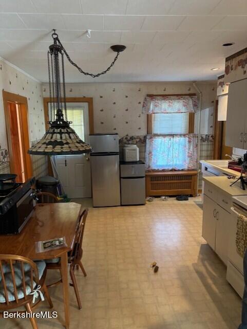 kitchen featuring a healthy amount of sunlight, ornamental molding, and stainless steel refrigerator