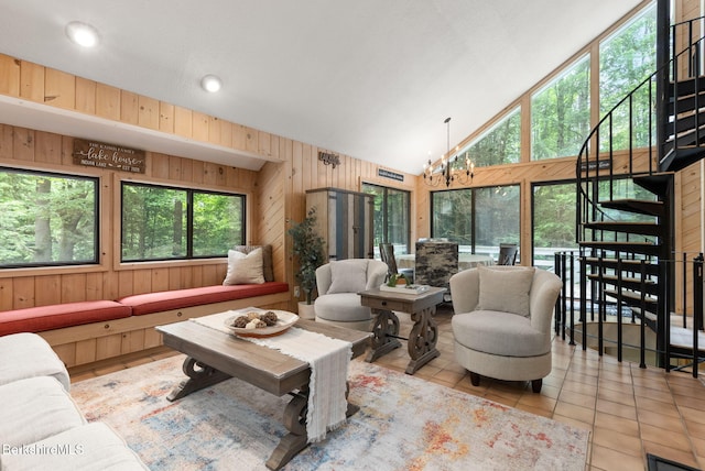 454 Seneca Dr, Becket, MA 01223 - tiled living room featuring wood walls, a chandelier, high vaulted ceiling, and stairway