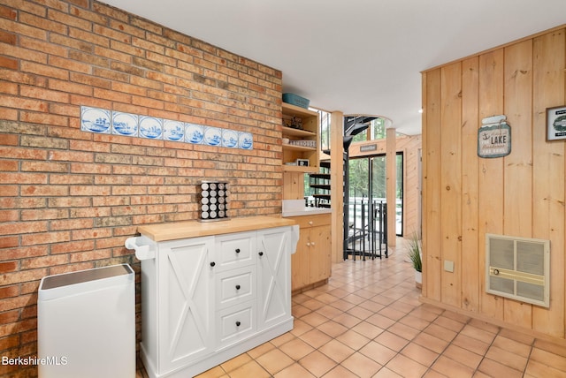 454 Seneca Dr, Becket, MA 01223 - kitchen featuring open shelves, wooden walls, light tile patterned flooring, heating unit, and white cabinetry
