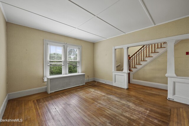 34-36 Crandall St, Adams, MA 01220 - empty room with radiator heating unit, wood-type flooring, stairway, and ornate columns