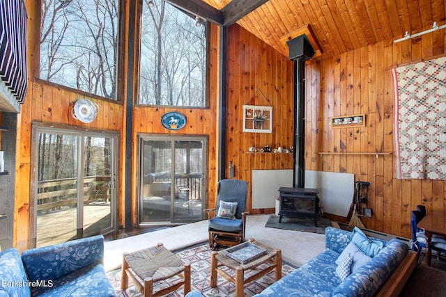 living room with a wood stove, high vaulted ceiling, wood walls, carpet floors, and wood ceiling