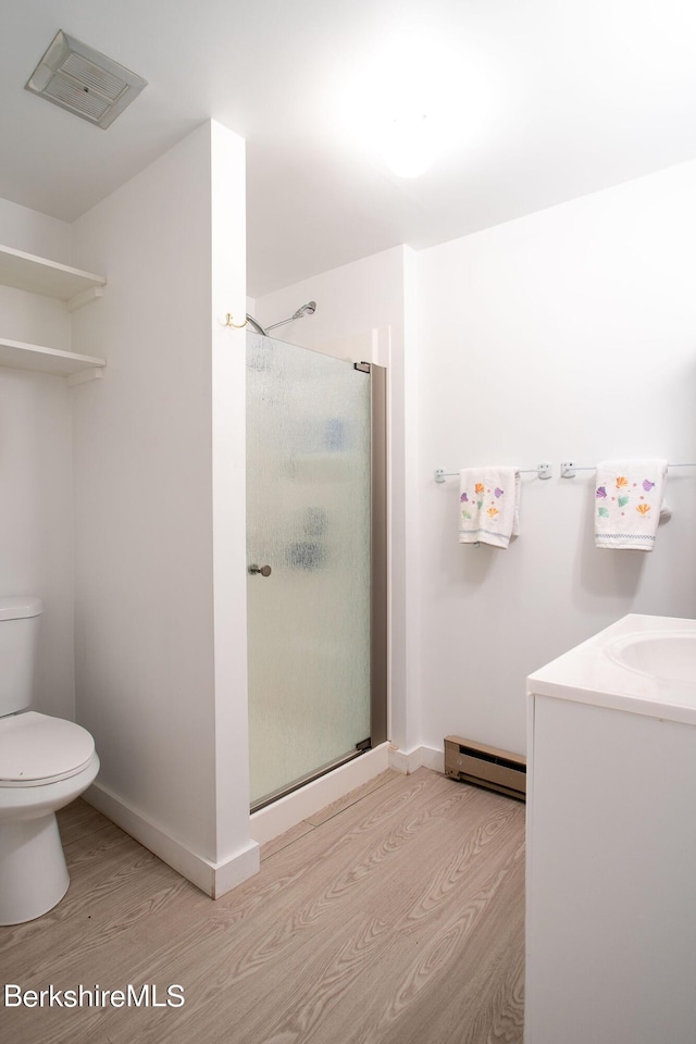 bathroom with vanity, hardwood / wood-style flooring, a shower with shower door, and a baseboard heating unit