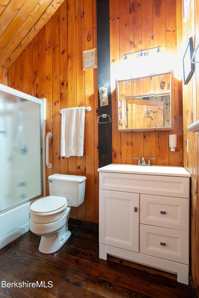 full bathroom with wooden walls, vanity, bath / shower combo with glass door, and vaulted ceiling