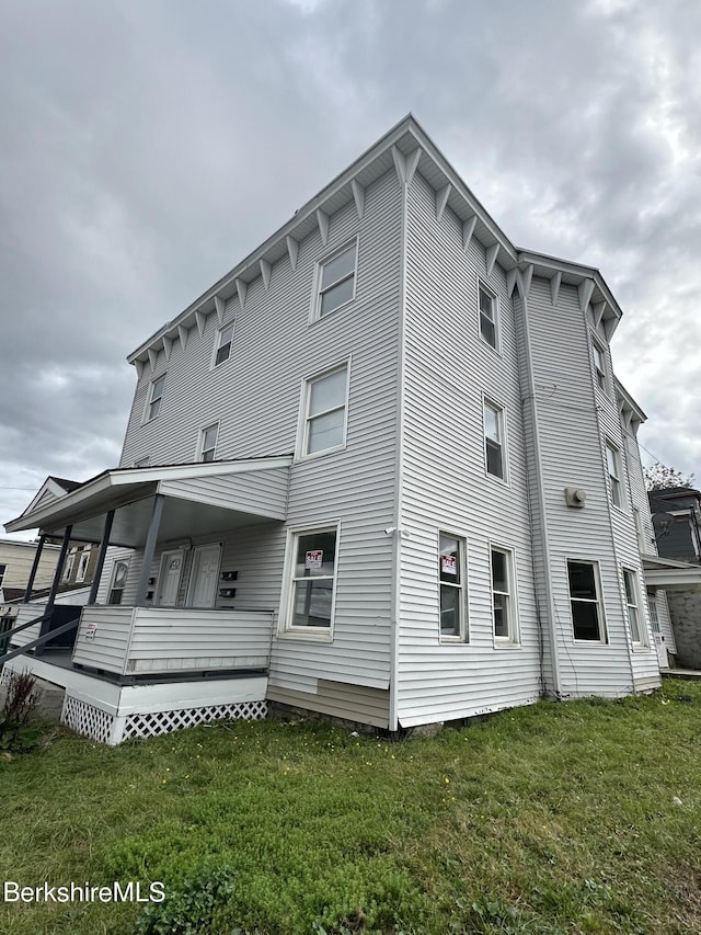 rear view of property featuring a yard and covered porch