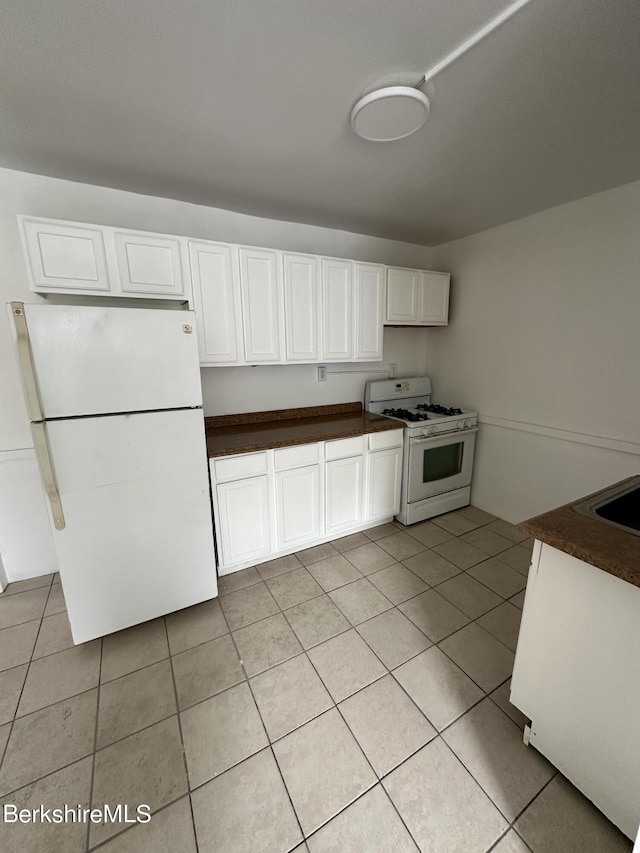 kitchen featuring white cabinetry, light tile patterned flooring, and white appliances