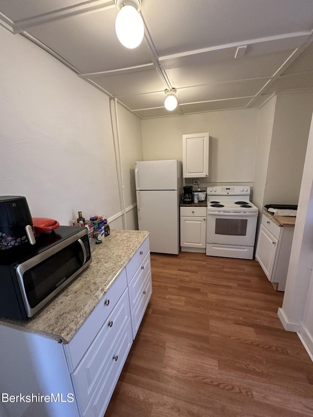 kitchen with white cabinetry, dark hardwood / wood-style flooring, light stone countertops, and white appliances