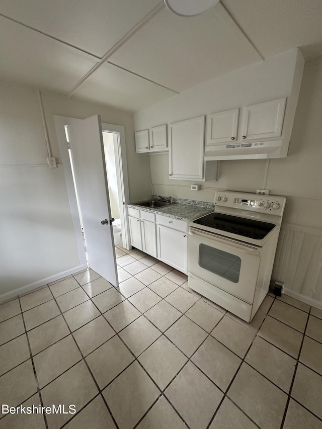 kitchen with white electric range, light tile patterned floors, white cabinetry, and sink