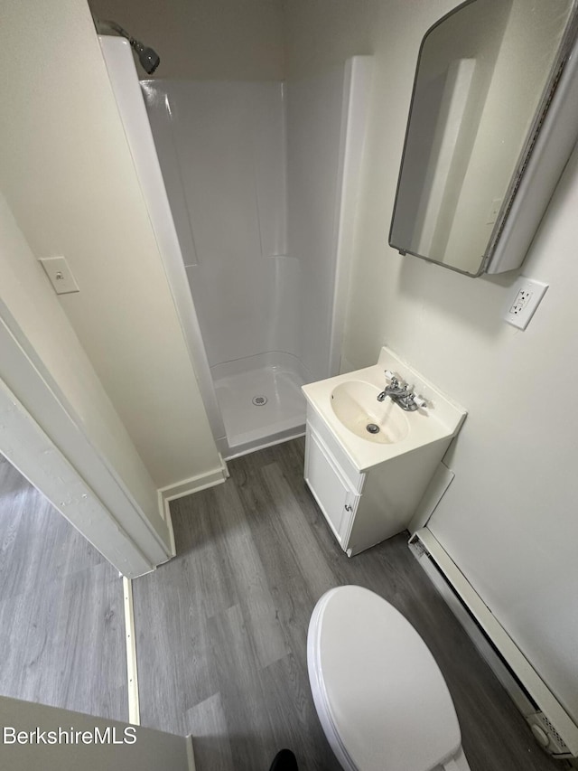 bathroom with a baseboard radiator, a shower, toilet, vanity, and hardwood / wood-style flooring