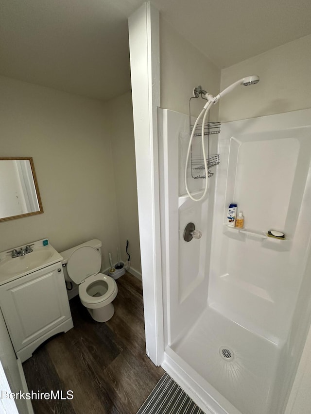 bathroom featuring hardwood / wood-style floors, vanity, toilet, and walk in shower