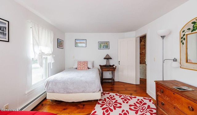 bedroom featuring wood-type flooring, a baseboard radiator, and multiple windows