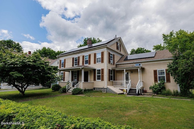 view of front of house with covered porch, solar panels, and a front lawn