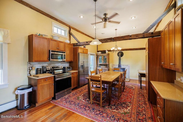 kitchen with hardwood / wood-style floors, pendant lighting, a baseboard heating unit, tasteful backsplash, and stainless steel appliances